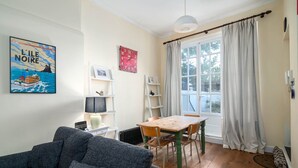 Una sala de estar acogedora con un sofá, una mesa de madera y una ventana con cortinas.