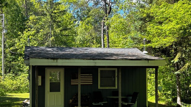Eine kleine Holzhütte mit Veranda, Tür und Fenster.
