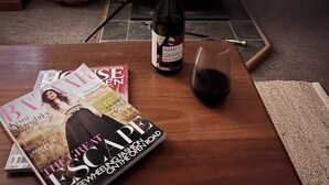A cozy room with a fireplace, a bottle of wine, and magazines on a wooden table. - Cosy Pet Friendly Beach Cottage (Golden Beach)