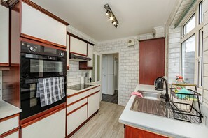 A kitchen with a built-in oven, a sink with a dish rack, and a window with a view. - House - Sleeps 10 - Parking - Garden (Colchester)