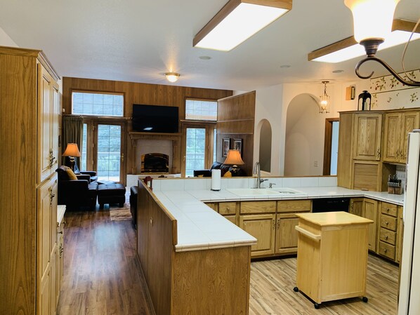 A spacious kitchen with wooden cabinets, a central island, and a built-in TV. - 5 bd, 4 bth, A/C, new mattresses, hot tub, waterfalls, walk to town, trails! (Green Mountain Falls)