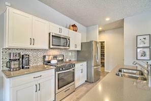 A modern kitchen with white cabinets, stainless steel appliances, a microwave, stove, and a refrigerator.