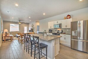 A spacious kitchen with a large island, white cabinets, stainless steel appliances, and a dining area with a table and chairs.
