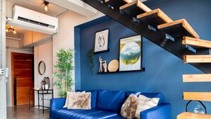 Een moderne woonkamer met een blauwe bank, een trap en kunst aan de muur.