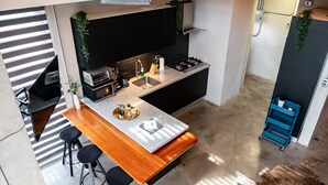 Een moderne keuken met een centraal eiland, zwarte kastjes en een roestvrijstalen spoelbak.