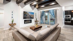 A modern living room with a sectional sofa, a fireplace, and a kitchen in the background. - VILLA WITH MASTER SUITE CLOSE TO SHOPPING 4 BR 3BA (EL PASO)