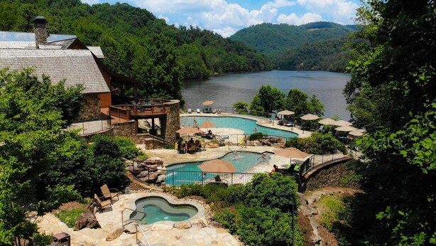 A resort with multiple swimming pools, a stone building, and a view of a lake surrounded by forest. - NEW High-Speed WiFi! Movie Theater, Pool Table & Hot Tub in Bear Lake Reserve!! (Tuckasegee)