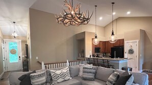 A modern living room with a sectional sofa, a wooden coffee table, and a unique antler chandelier. - NEW High-Speed WiFi! Movie Theater, Pool Table & Hot Tub in Bear Lake Reserve!! (Tuckasegee)