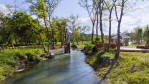 A serene outdoor area with a clear stream, surrounded by trees and a small building. - Dong'an Ziyuan Hotel (Zishui National Wetland Park High-Speed Railway Station Branch) (Dong'an)