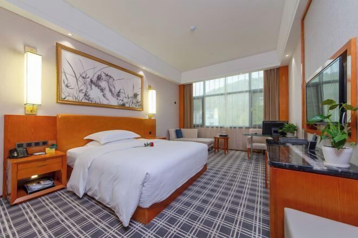 Una habitación de hotel con una cama grande, un escritorio, una silla y una televisión.