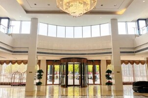 Un hall espacioso con puerta giratoria, amplias ventanas y un candelabro.