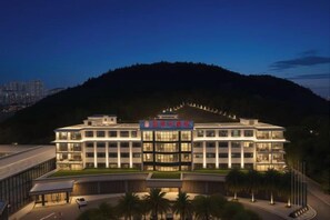 A multi-story hotel with a modern architectural design, featuring a prominent entrance and a landscaped area with palm trees. - Dong'an Ziyuan Hotel (Zishui National Wetland Park High-Speed Railway Station Branch) (Dong'an)