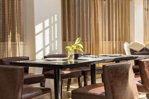 A dining area with a long table, multiple chairs, and a vase with a plant. - Dong'an Ziyuan Hotel (Zishui National Wetland Park High-Speed Railway Station Branch) (Dong'an)