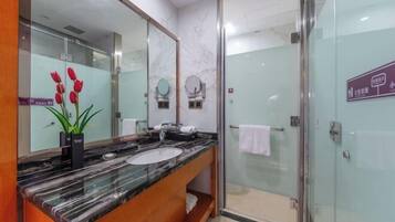 Une salle de bain moderne avec un lavabo en marbre, un grand miroir et une douche à parois de verre.