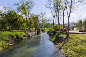 Ein Fluss fließt durch einen Park mit Bäumen und einer Holzbrücke.