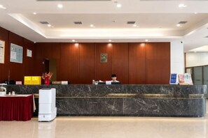 A hotel reception area with a marble counter, a red table, and a white air conditioner. - Dong'an Ziyuan Hotel (Zishui National Wetland Park High-Speed Railway Station Branch) (Dong'an)