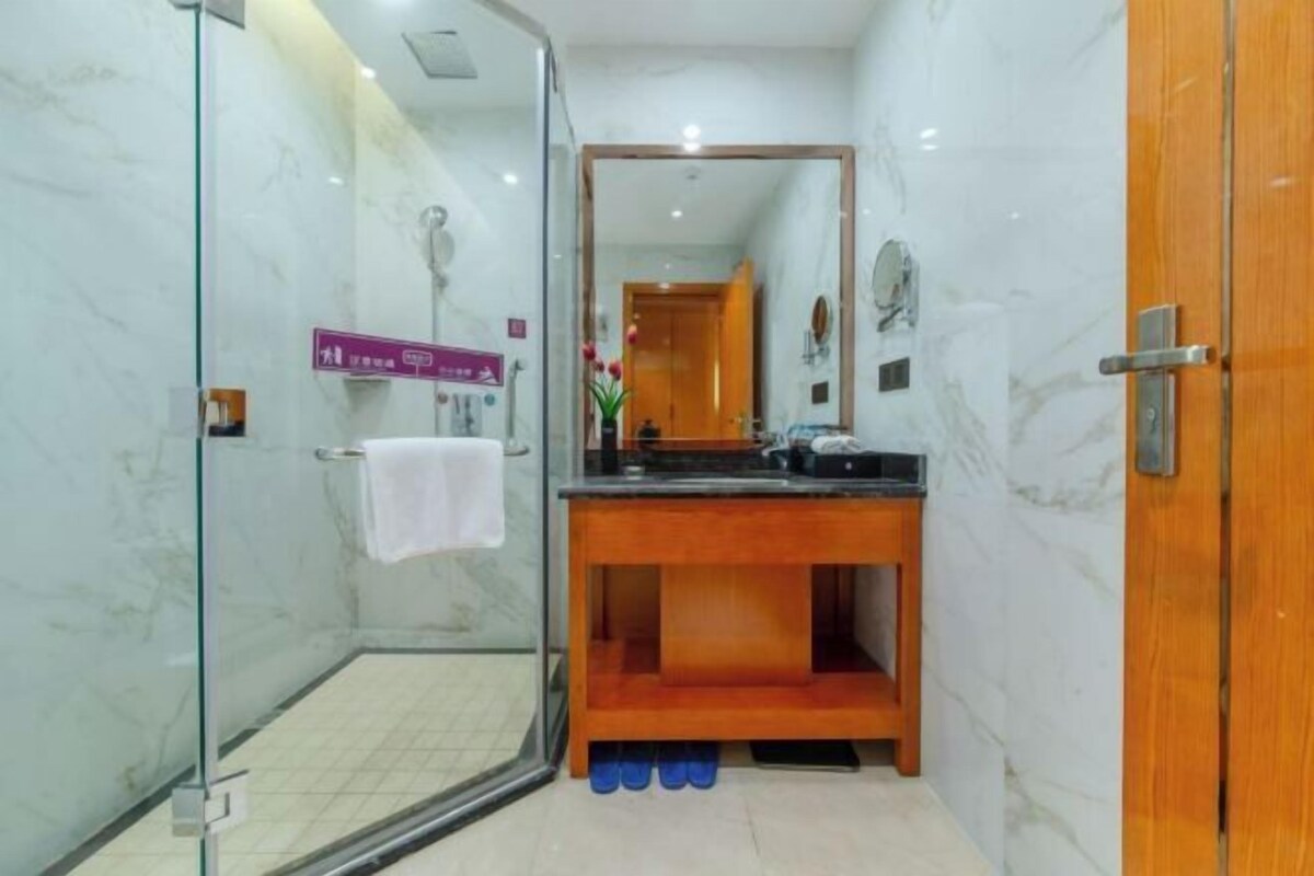Un baño con cabina de ducha de vidrio, tocador de madera y espejo.