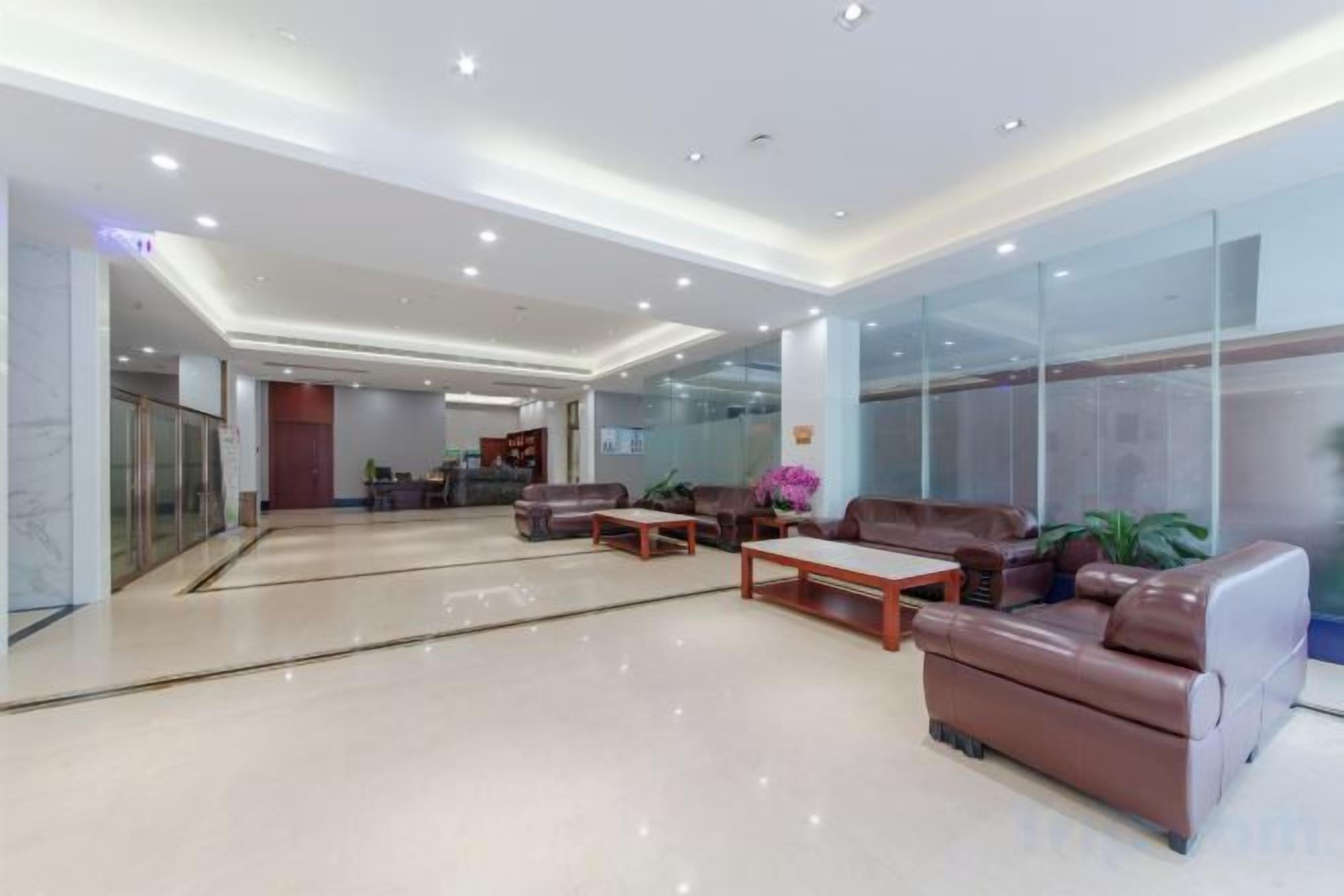A modern lobby with seating areas, a reception desk, and glass walls.