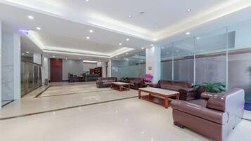 A modern lobby with seating areas, a reception desk, and glass walls.