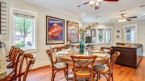 A dining area with a round wooden table, chairs, and a vase of flowers. - Ecco Domani by AvantStay | Gorgeous Home w/ Pool, Balcony in Great Location (Key West)