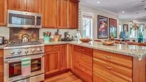 A kitchen with wooden cabinets, a stainless steel stove, and a granite countertop. - Ecco Domani by AvantStay | Gorgeous Home w/ Pool, Balcony in Great Location (Key West)