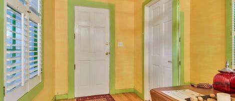 A hallway with wooden flooring, green-painted walls, and white doors.