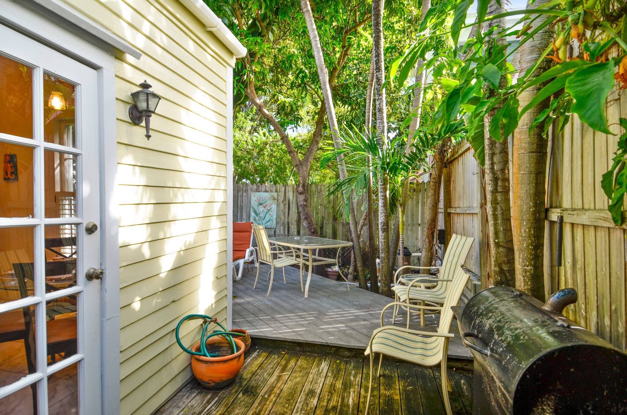 A wooden deck with outdoor furniture, a barbecue grill, and a garden area with trees and plants.