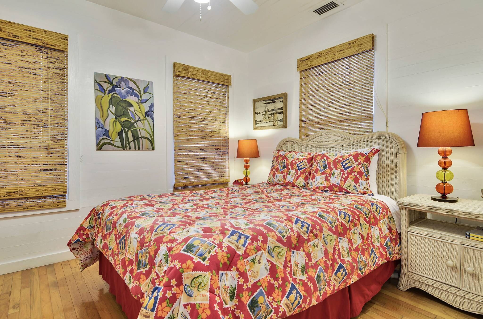 A bedroom with a large bed, two bedside tables with lamps, and artwork on the walls.
