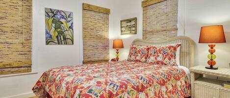 A bedroom with a large bed, two bedside tables with lamps, and artwork on the walls.