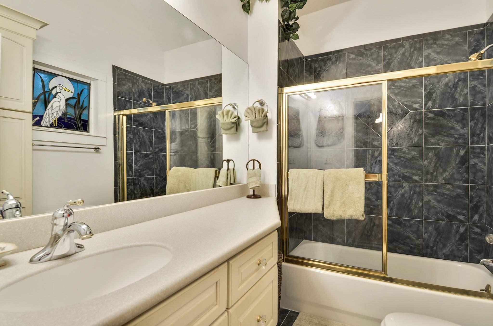 A modern bathroom with a large mirror, a sink, a bathtub with a glass enclosure, and a shower.