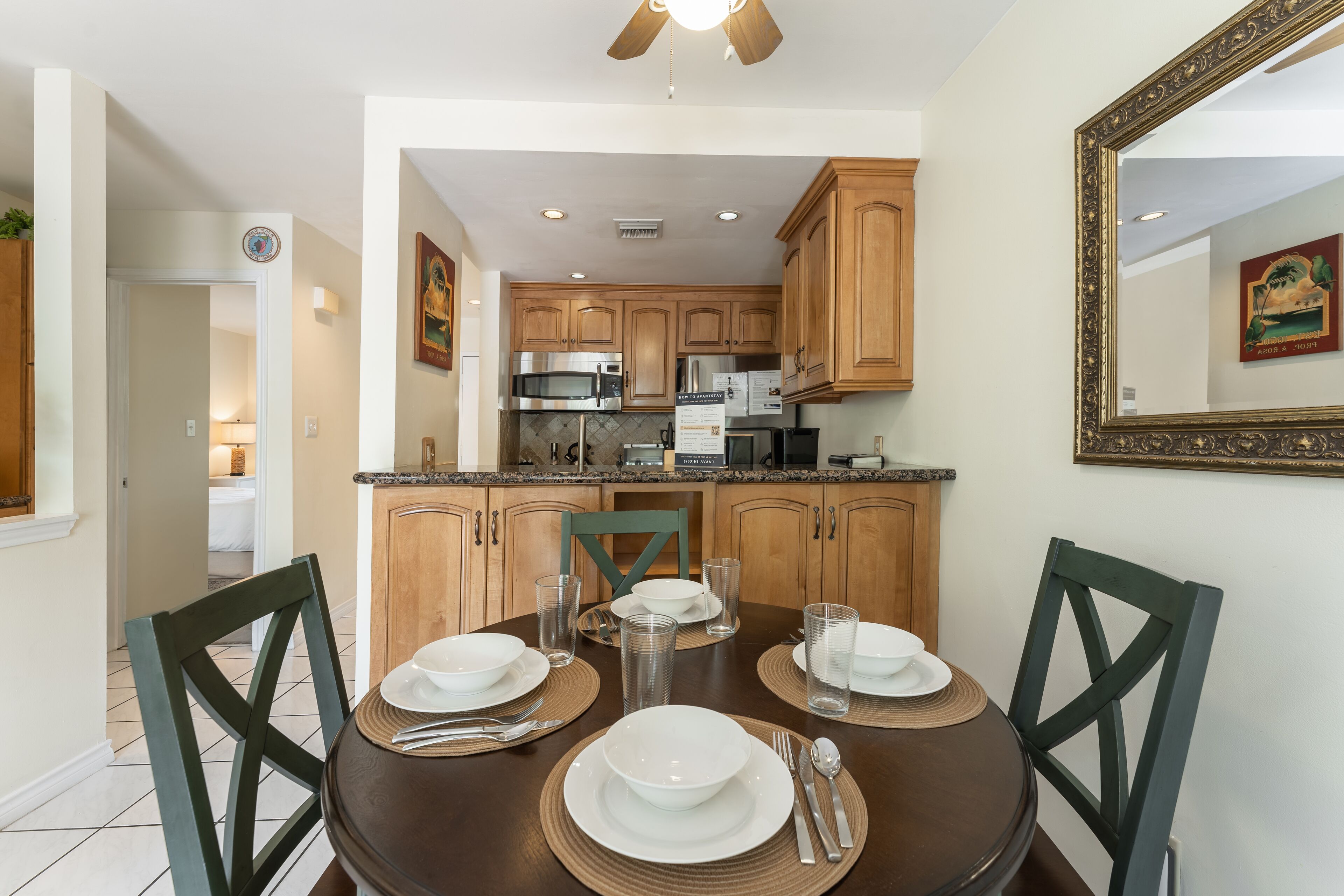 A dining area with a round table set for four, surrounded by wooden chairs.
