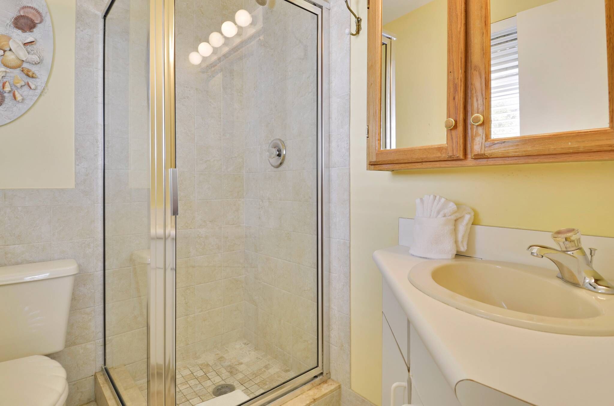 A bathroom with a glass-enclosed shower, a sink, and a toilet.