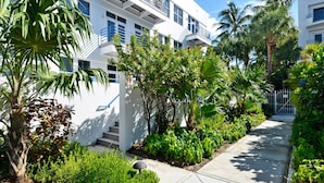 A modern building with balconies, surrounded by lush greenery and palm trees. - Truman's Hideaway | Top Location w/ Patio, Pool Access & BBQ | Month Long Stays (Key West)