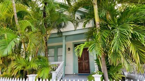 Een huis met een witte picket fence, een veranda met houten spijlen en een groene deur.