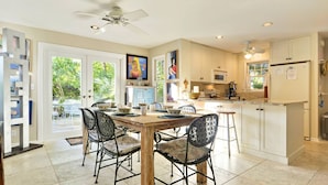 A spacious kitchen with white cabinets, a wooden dining table, and black chairs. - Artist Garden | Great Location w/ Balcony, Shared Pool & BBQ! | Month Long Stays (Key West)