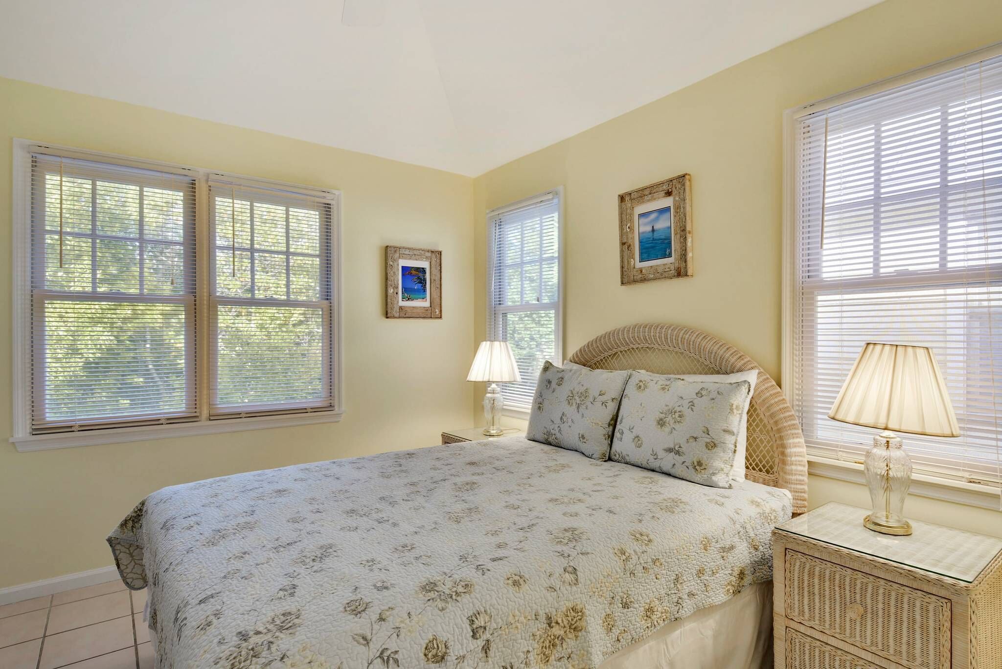 A bedroom with a large bed, two bedside tables, and a window with blinds.