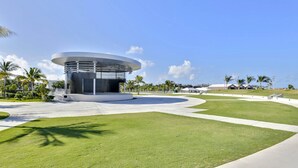 Un edifici modern de disseny circular, envoltat d'un jardí ben cuidat i palmeres.