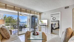 Un soggiorno moderno con un tavolino in vetro, divani e un balcone con vista sull'oceano.