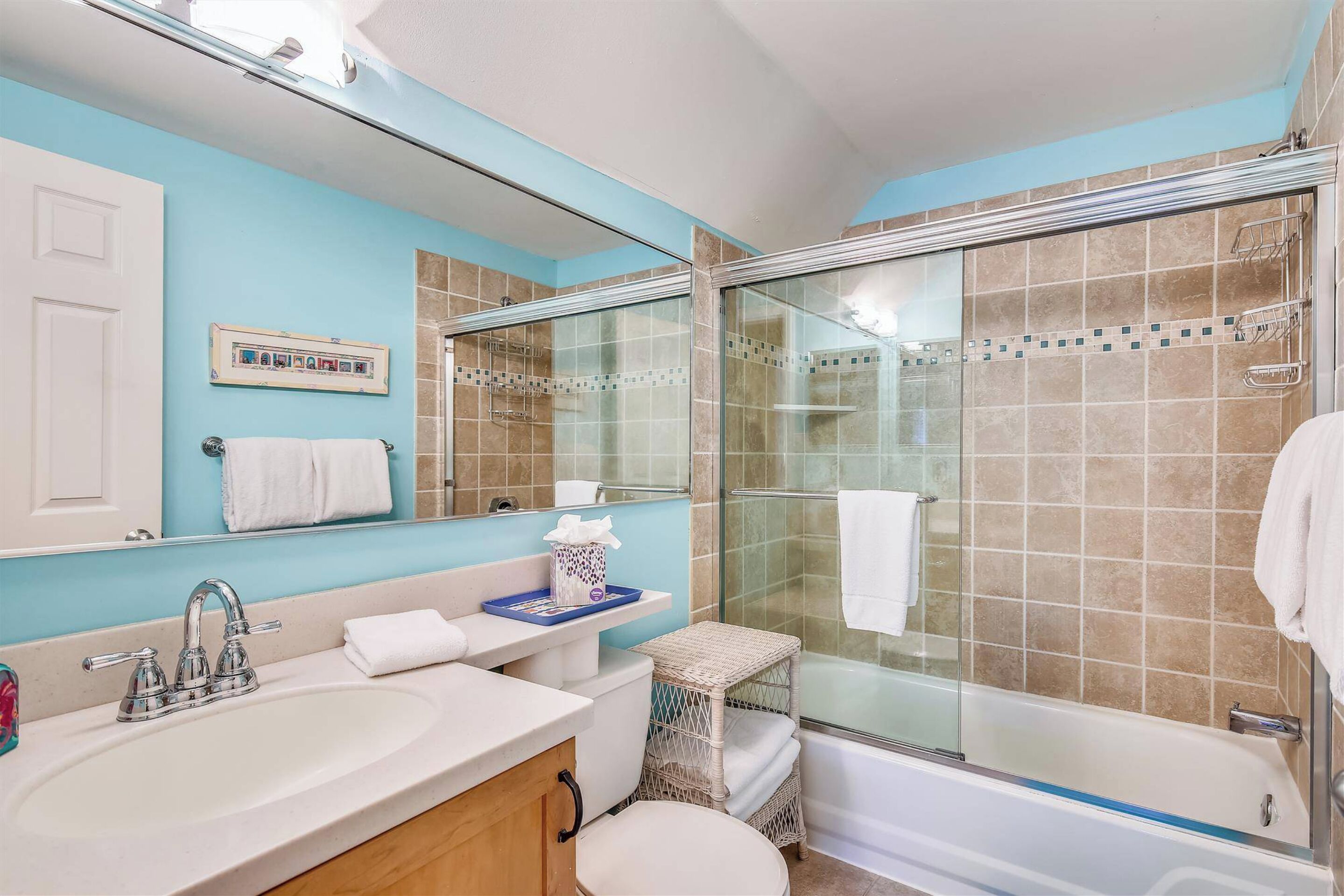 Een badkamer met een douchecabine, een wastafel met spiegel en een toilet.