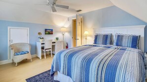 Ein Schlafzimmer mit Bett, Sessel, Schreibtisch und Deckenventilator.