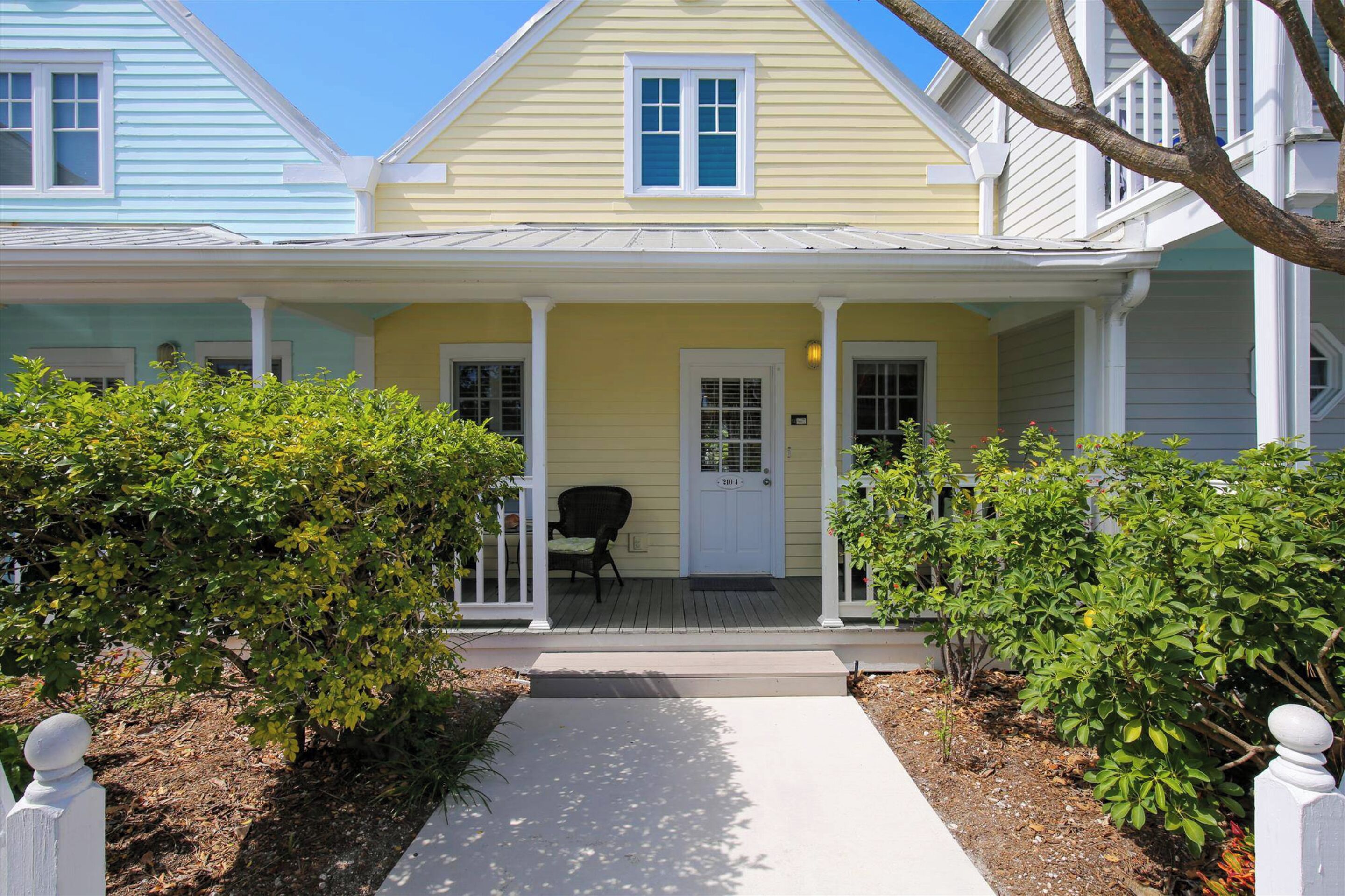 A two-story house with a porch, a front door, and a small chair.