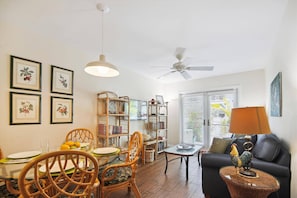 A living room with a dining area, a bookshelf, and a ceiling fan.