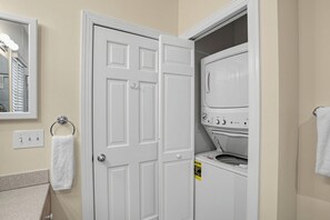 A laundry room with a white door, a washing machine, and a towel rack.