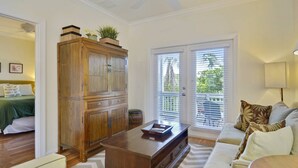 Una sala de estar con un mueble de madera, un sofá, una mesa de centro y una puerta que da a un balcón.