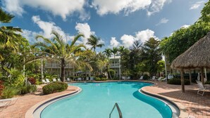 A swimming pool with lounge chairs and palm trees.
