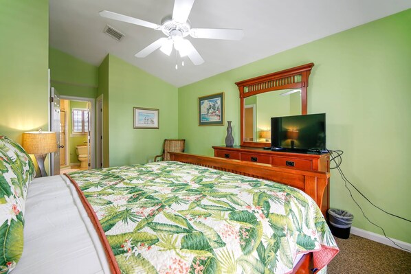 A bedroom with a bed, a television, a dresser, and a ceiling fan.