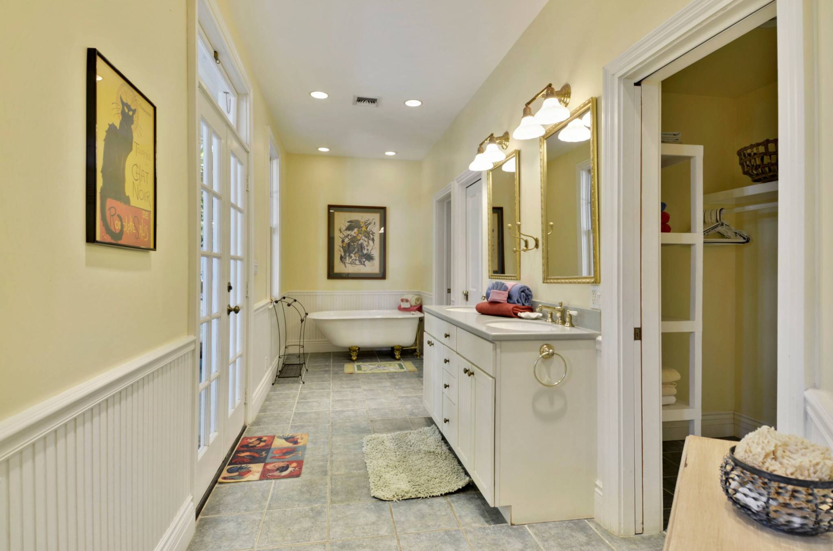 A bathroom with a bathtub, vanity, and a large mirror.