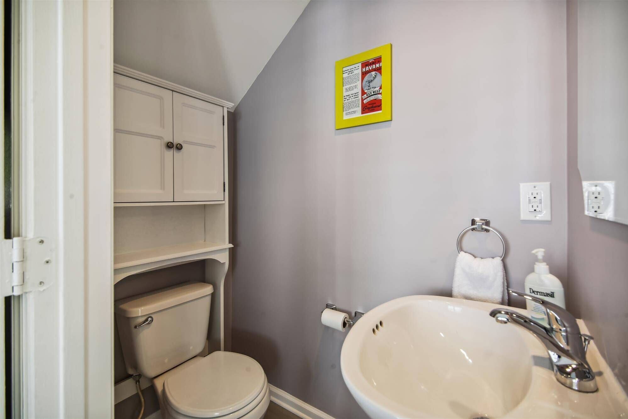 Et badeværelse med toilet, vask og skab.