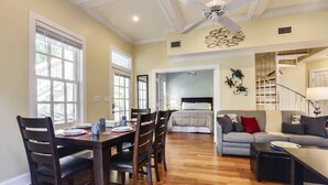 A spacious living area with a dining table, chairs, a sofa, and a staircase leading to another level. - Lazy Gecko by AvantStay | Walk to Duval St in Key West! | Month Long Stays Only (Key West)