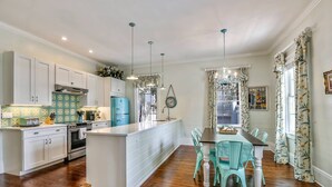 Una cocina con armarios blancos, un refrigerador azul y un comedor con sillas turquesa.